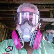 A middle aged man wearing colored pink face mask from a pest control service company